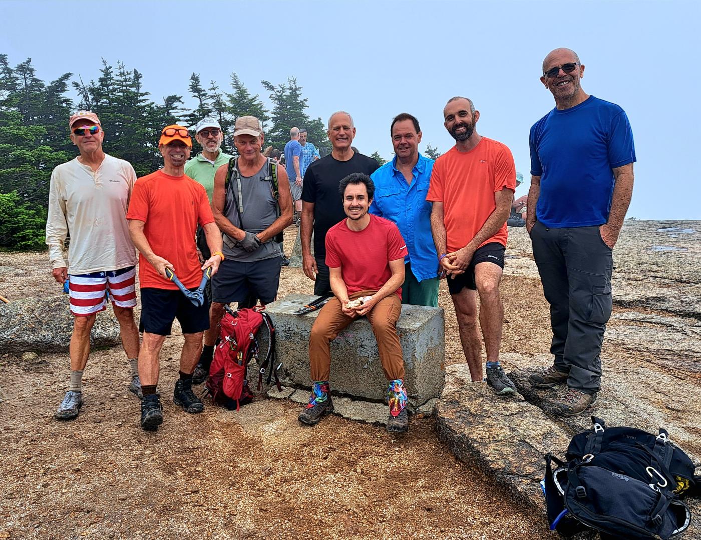 GayOutdoors members gathered at a summit marker on a foggy White Mountains peak
