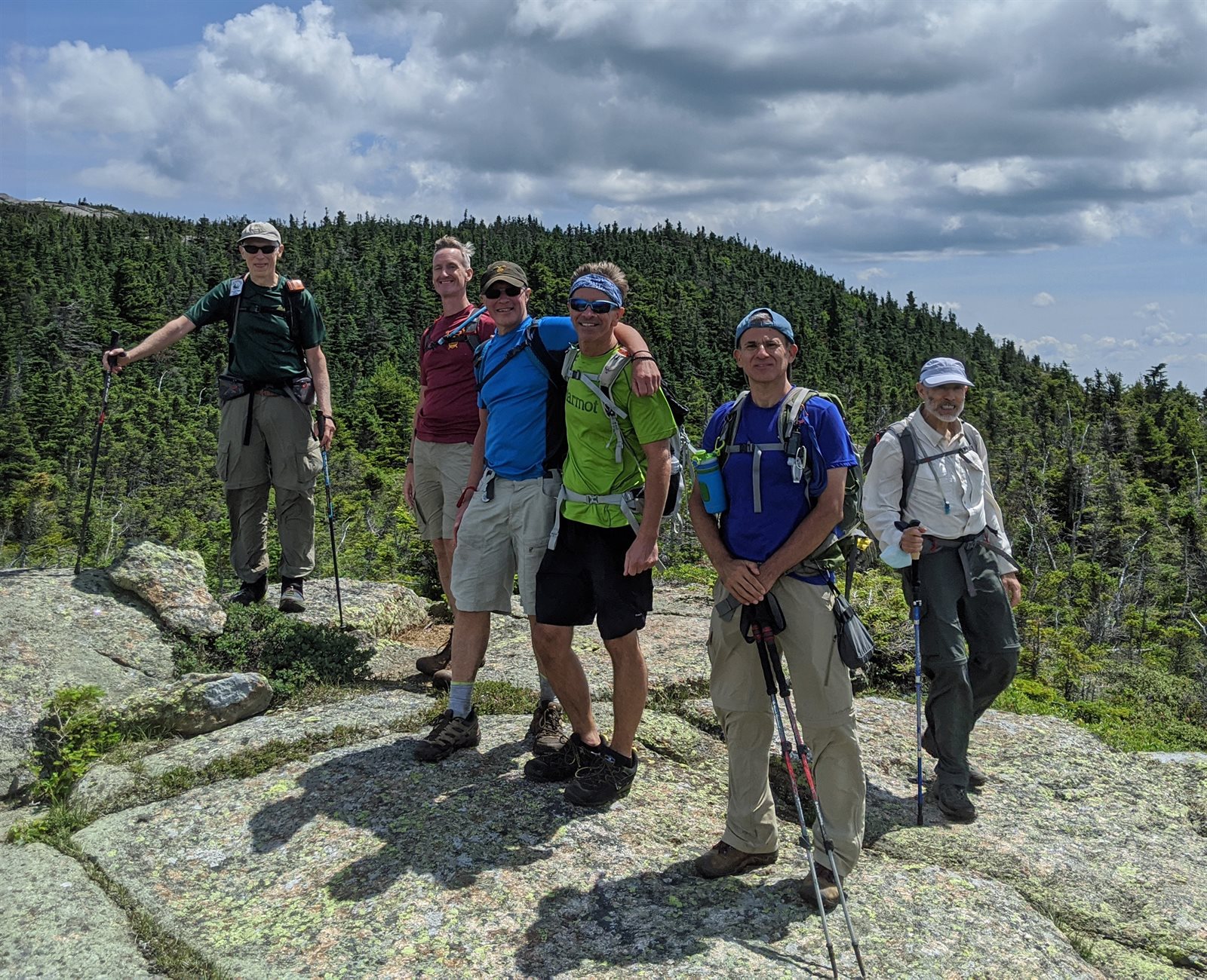 A group of GayOutdoors hikers together on a rocky mountain ledge