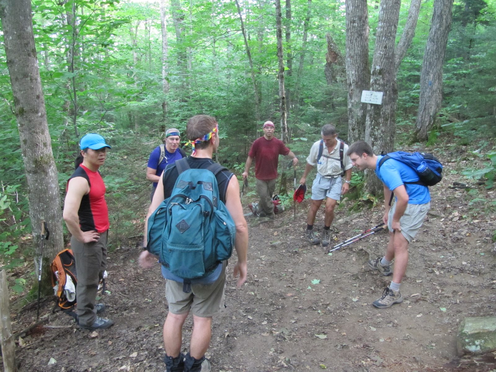 A group of GayOutdoors hikers gathered together on a wooded trail