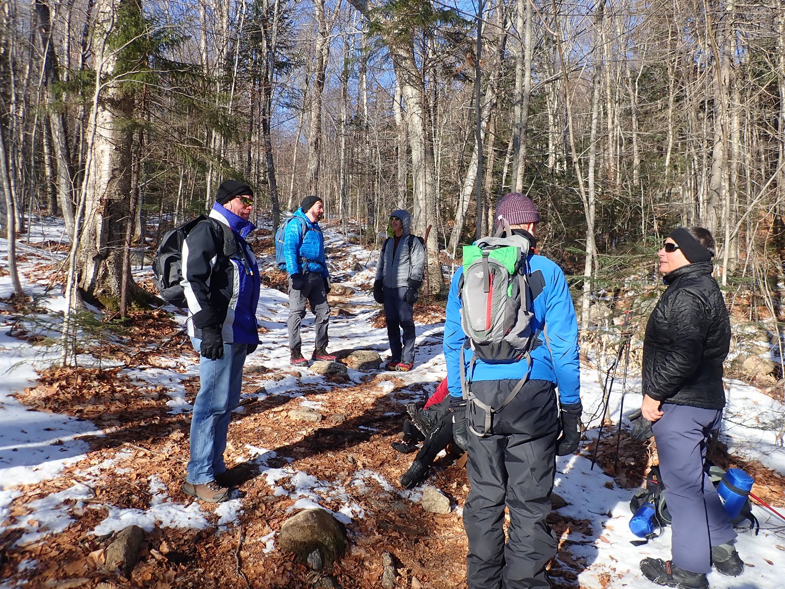 GayOutdoors hikers gathered on a snowy winter trail, waiting for the whole group to arrive