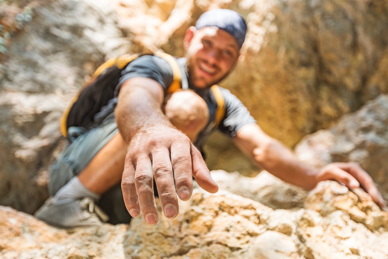 A smiling hiker reaching out a hand to help a fellow member up the rocks