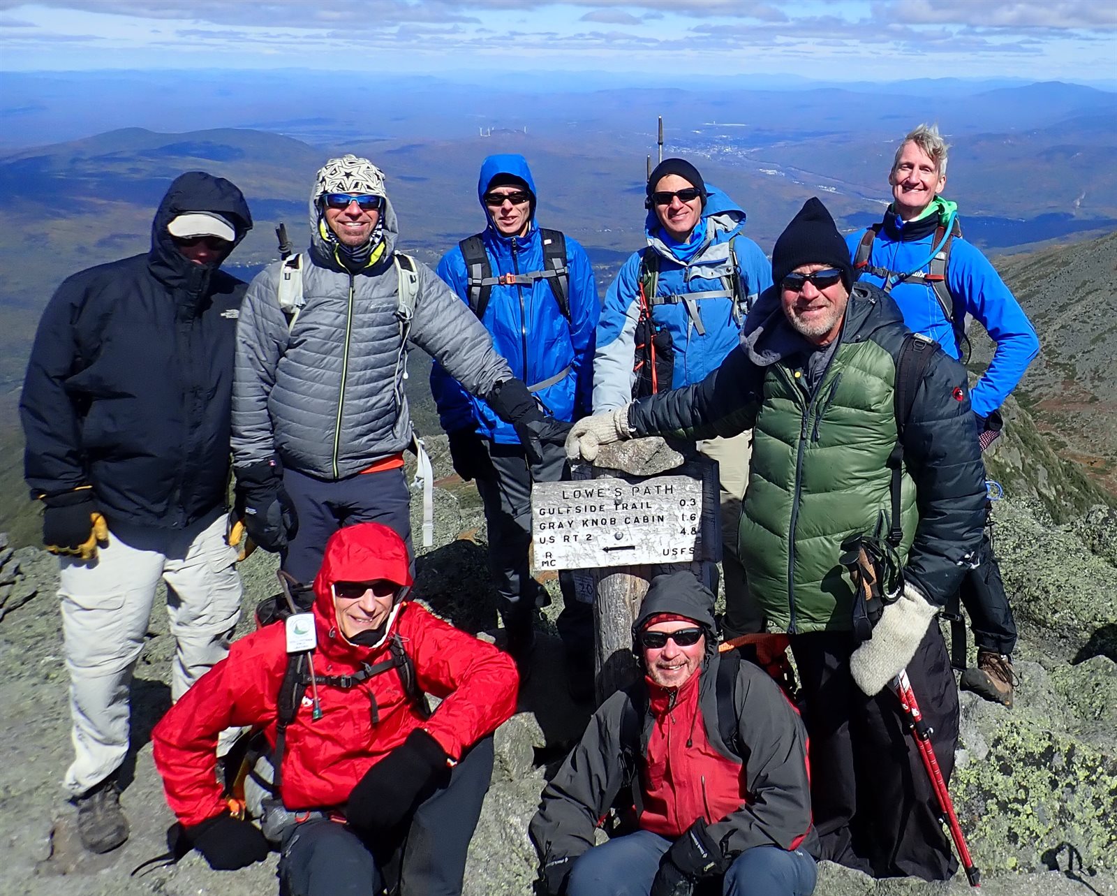 A group of GayOutdoors hikers in warm layers and hats at the Lowe's Path trail sign